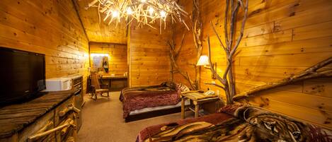 A cozy cabin room with two beds, a television, and a wooden interior.