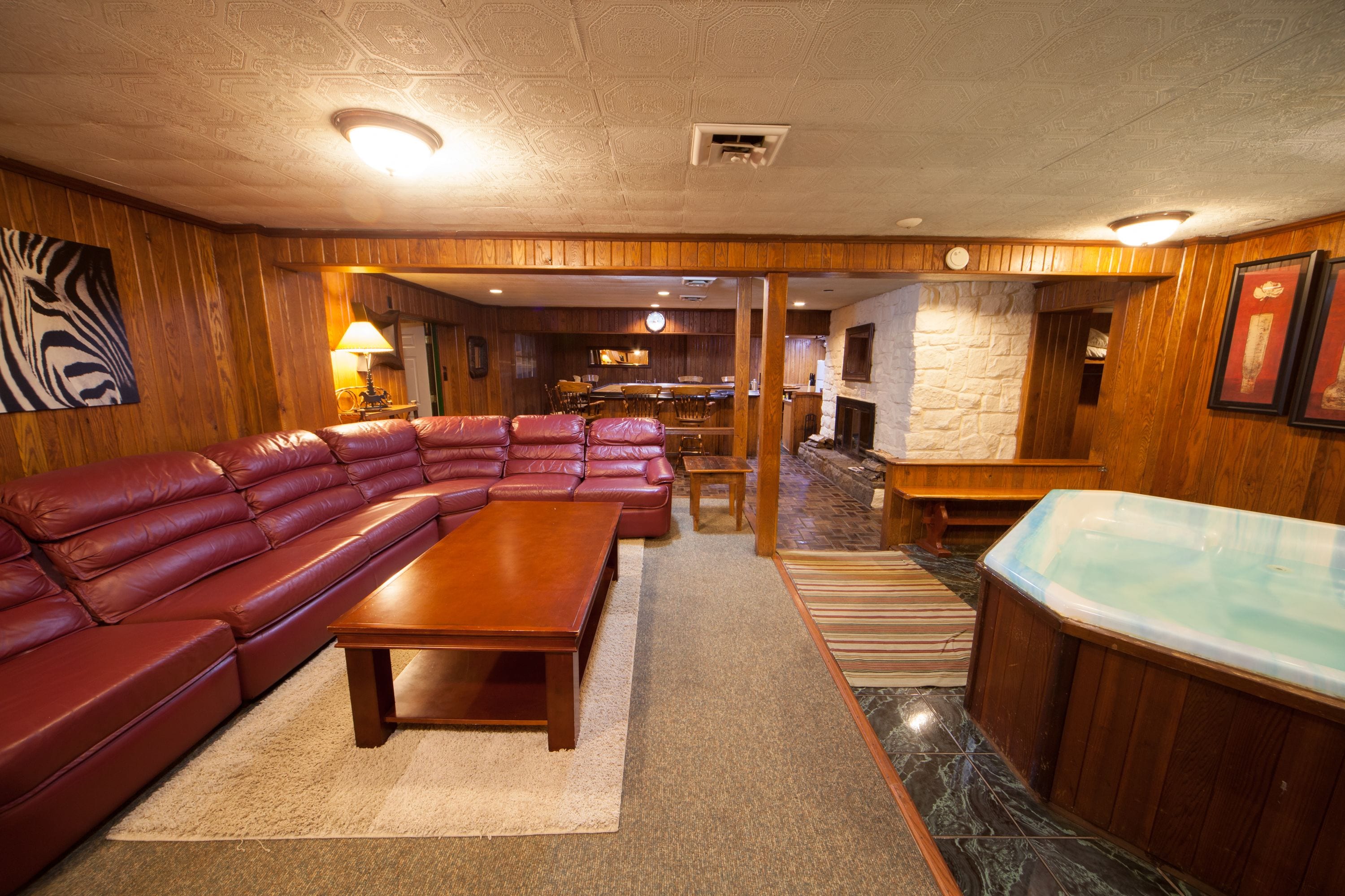 A spacious living room with a large leather sectional sofa, a wooden coffee table, and a hot tub.