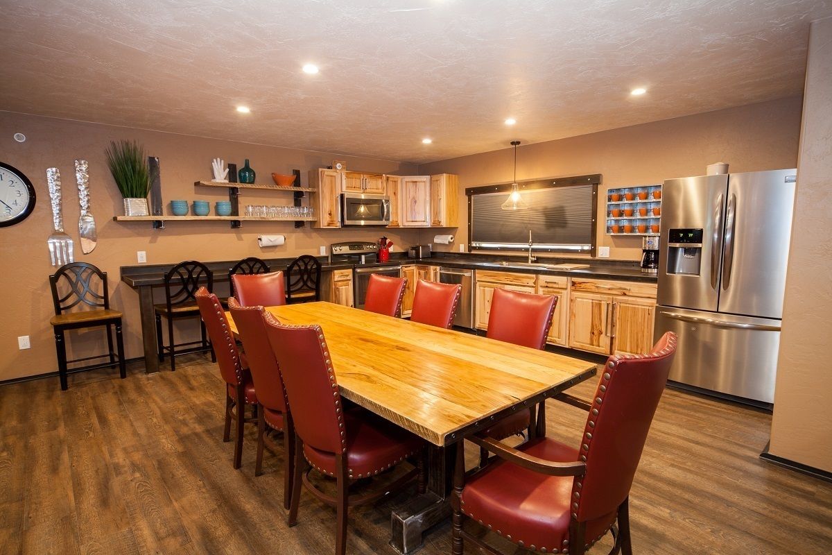 Una cocina moderna con una mesa de comedor de madera y sillas rojas, electrodomésticos de acero inoxidable y armarios de madera.