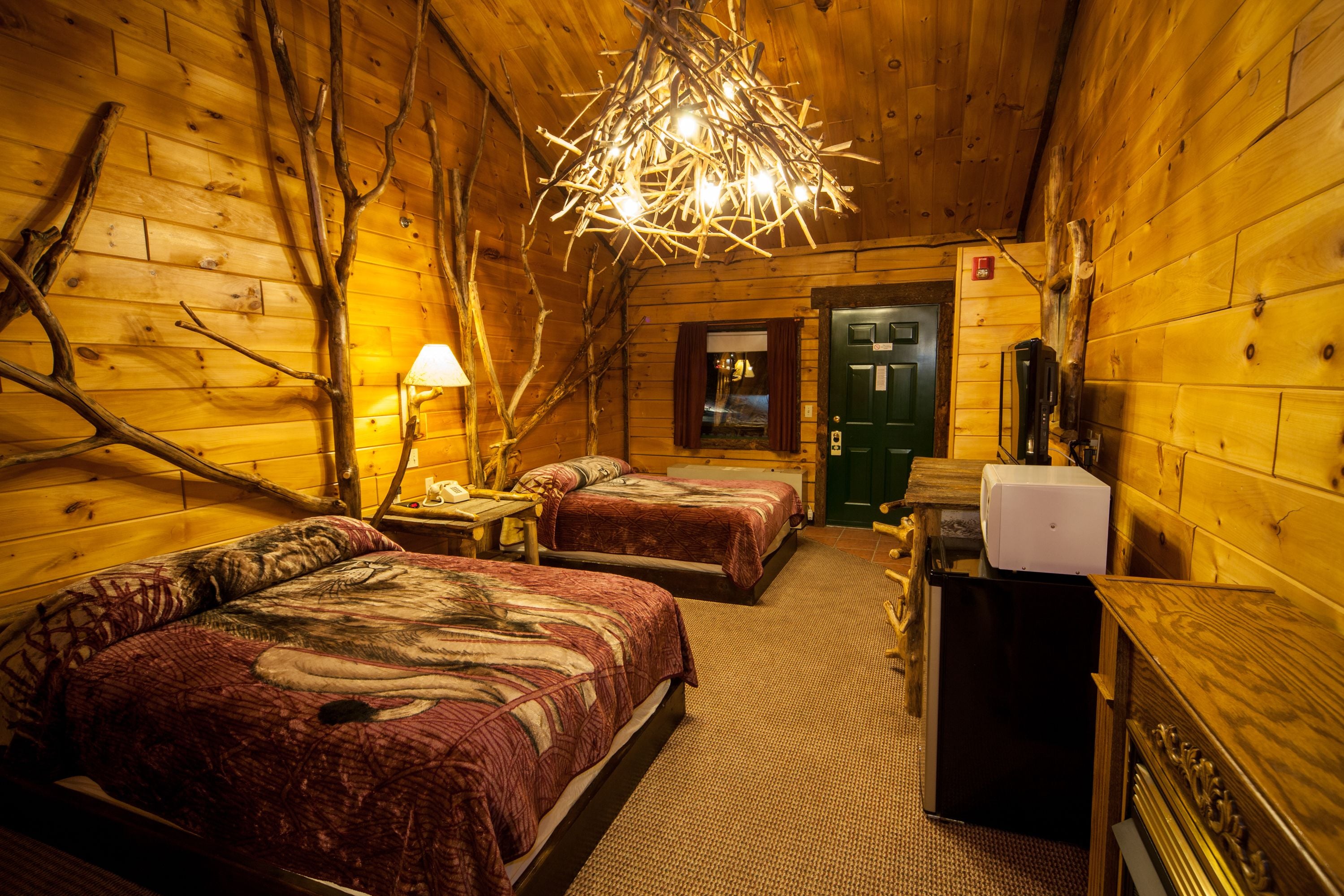 A cabin with two beds, a small table, a lamp, and a refrigerator.