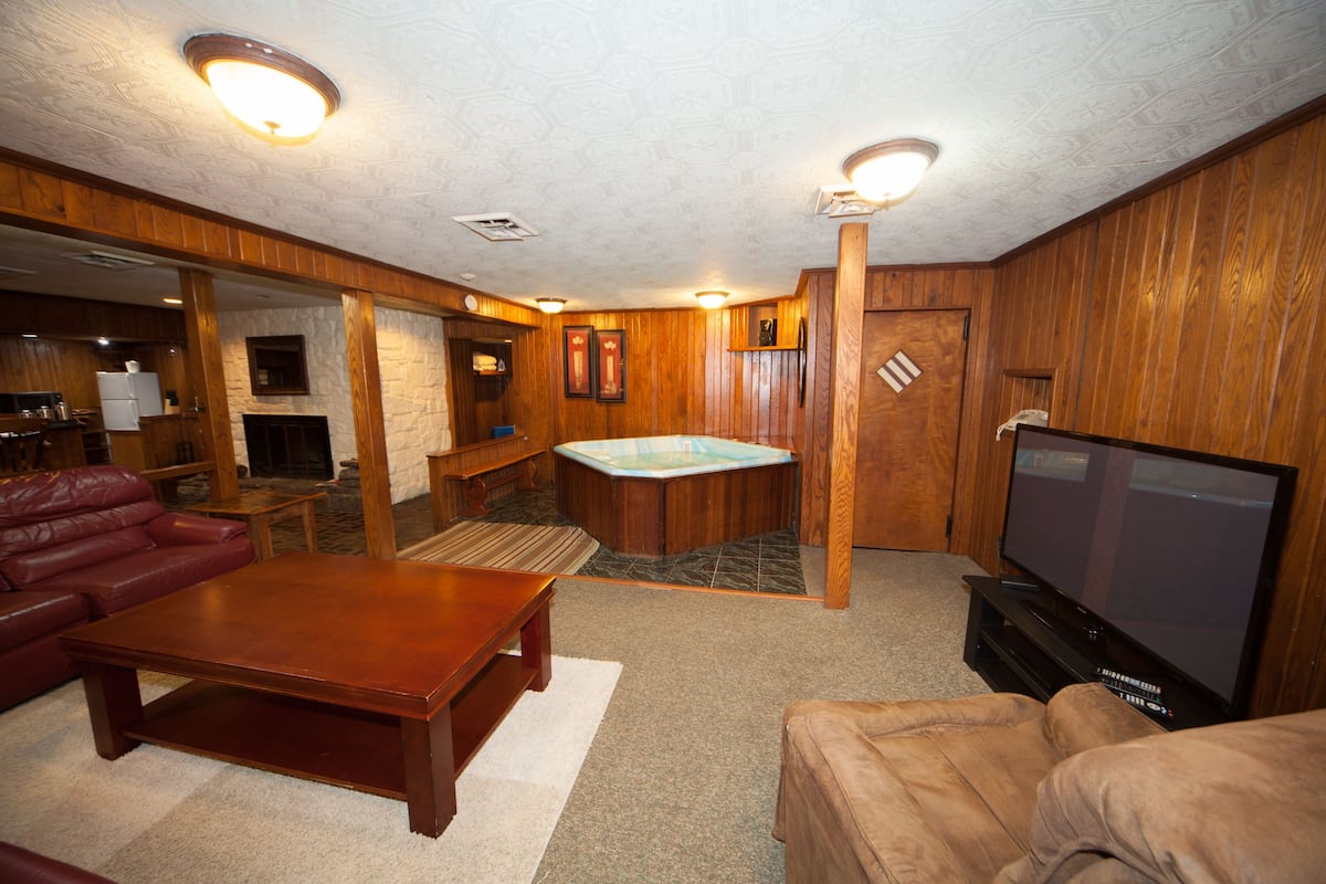 A living room with a wooden floor, a fireplace, a television, and a red leather couch.