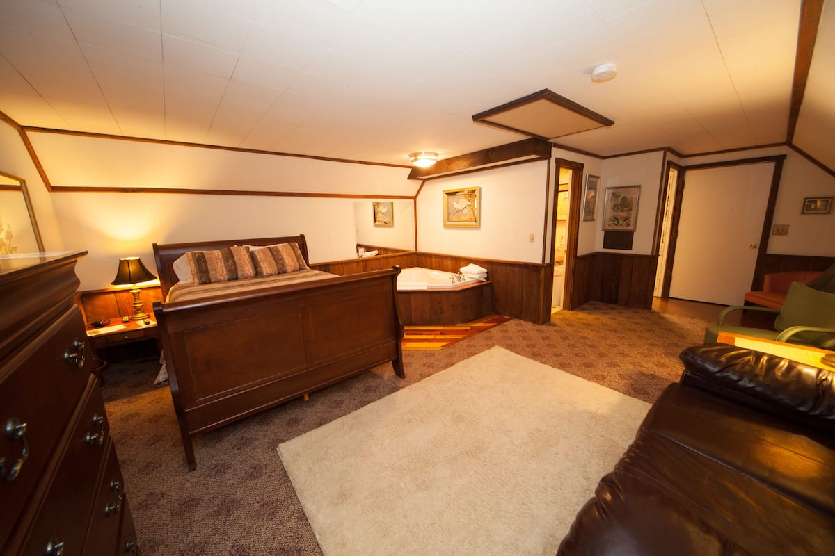 A bedroom with a wooden bed, bedside tables, a dresser, and a carpeted floor.