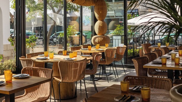 Un espace extérieur aménagé pour les repas, avec des meubles en osier et de la vaisselle en verre.