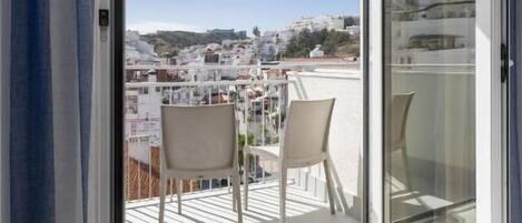 Un balcón con vistas despejadas de la ciudad, una mesa y dos sillas.