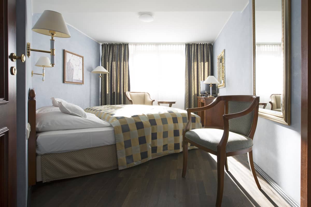 Une chambre d’hôtel avec deux lits, un bureau, une chaise et un grand miroir.