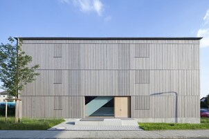 A modern building with a flat roof, vertical siding, and a large glass entrance.
