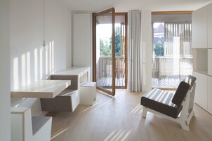 Una habitación moderna y bien iluminada con balcón, sofá y mesa de comedor.