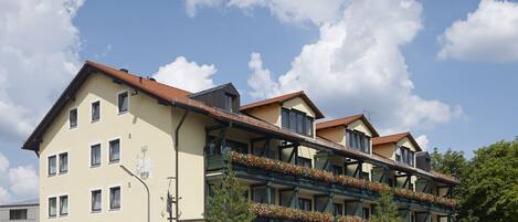 Un hotel de varios pisos con balcones, un restaurante y un letrero que indica una zona de 30 kilómetros.