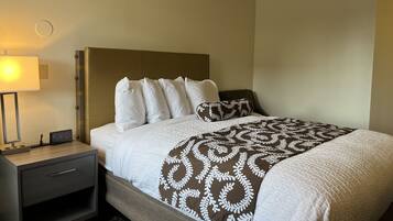 A hotel room with a bed, a nightstand, a lamp, and a digital clock.
