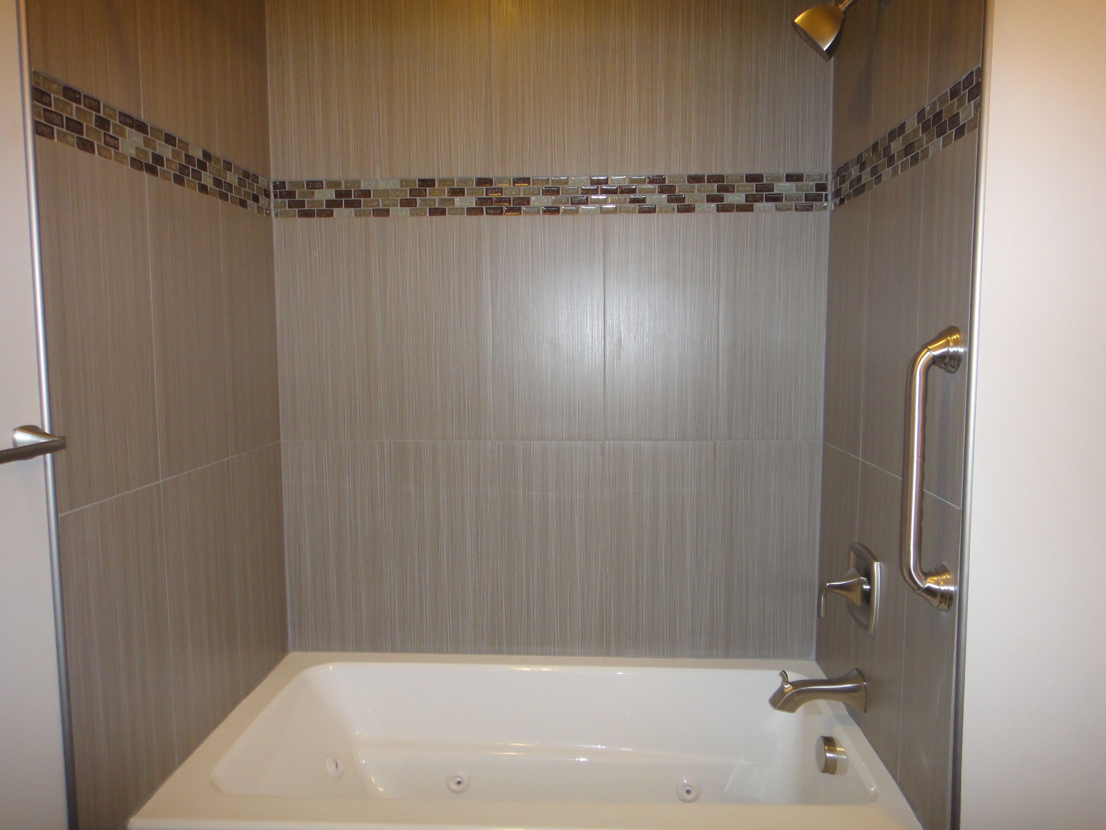 Une salle de bain avec une baignoire, un espace douche et un mur carrelé.