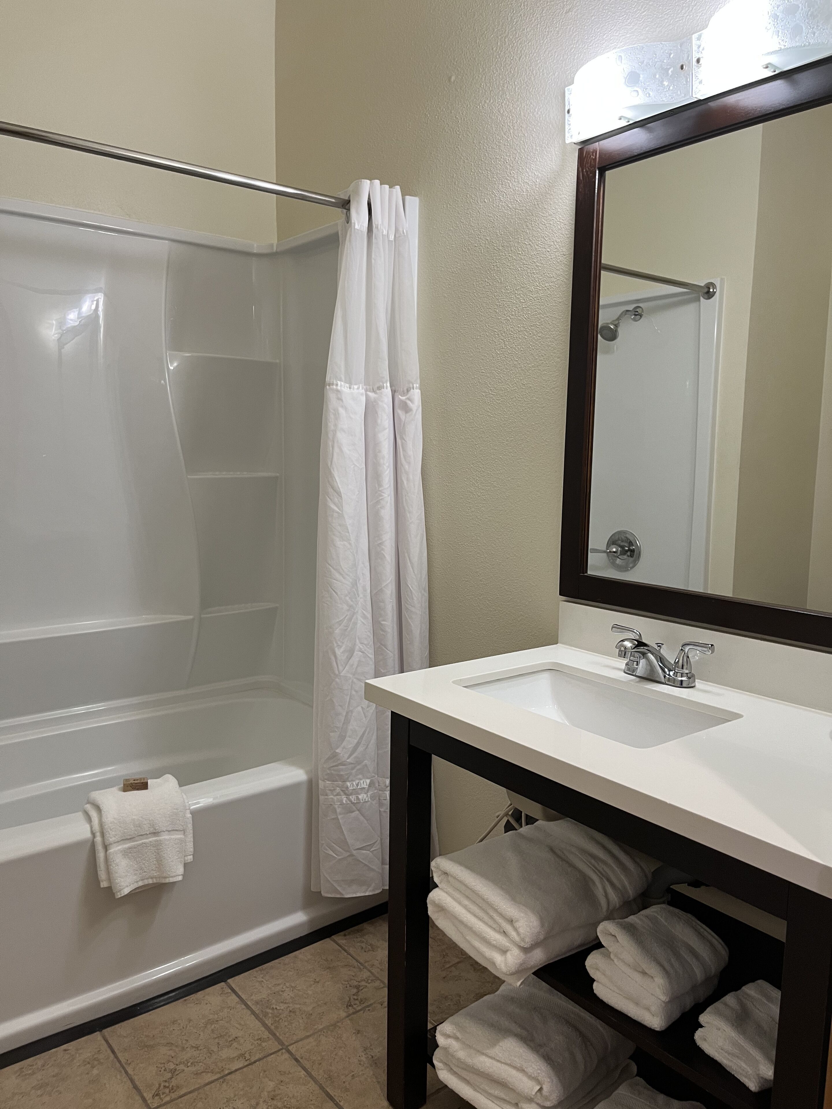 A bathroom with a glass-enclosed shower, a white sink, and a mirror above it.
