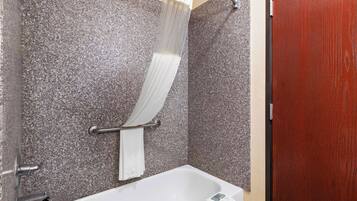 A bathroom with a white bathtub, a shower curtain, and a towel rack.