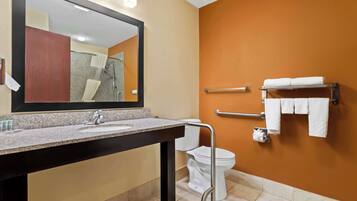 Un baño moderno con lavabo de granito, un espejo grande, un inodoro blanco y un perchero con varias toallas.