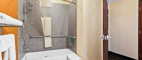 A modern bathroom with a bathtub, shower, and handrails.