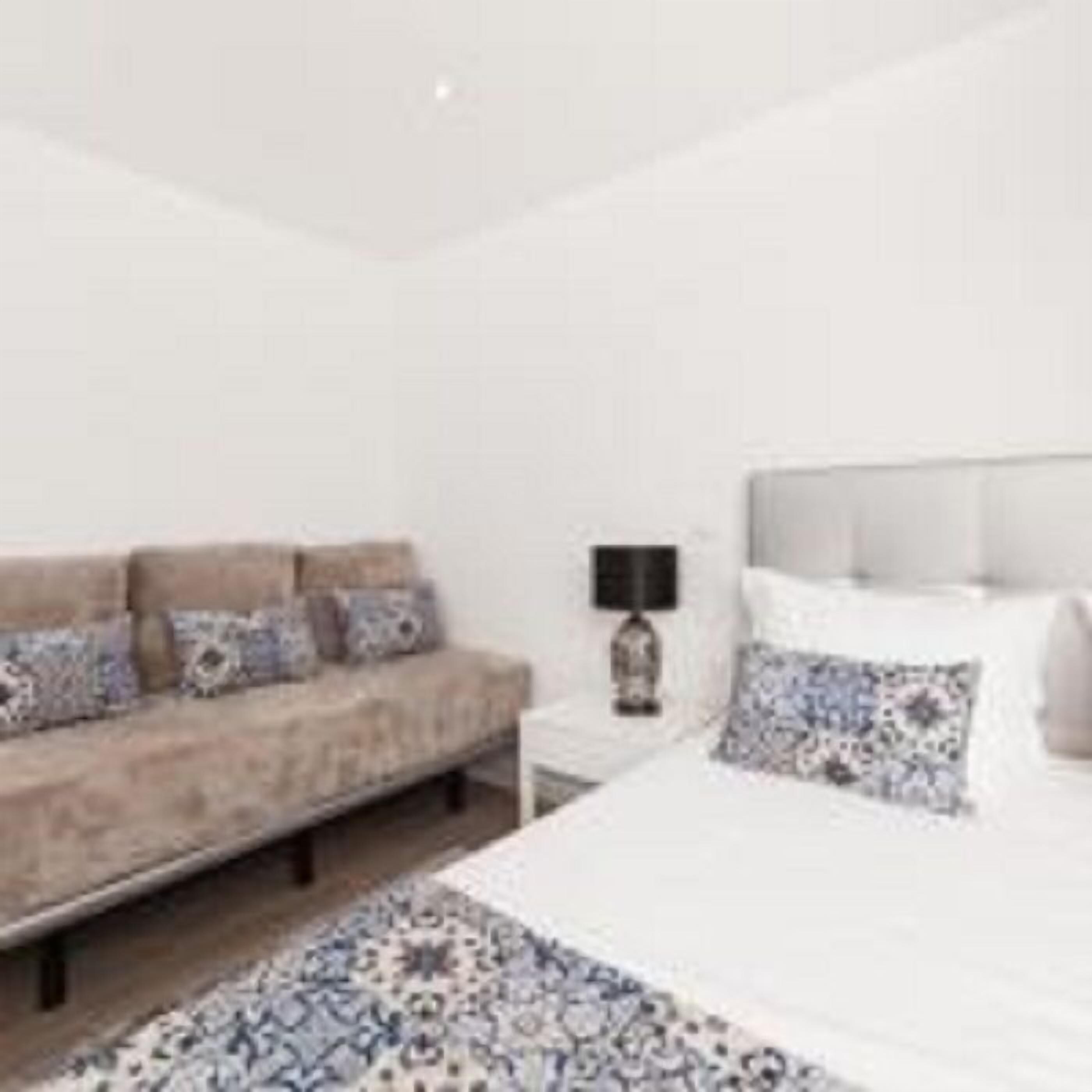 Un dormitorio moderno con una cama grande, un sofá y una mesita de noche.