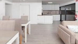 A modern living room with a sofa, a dining table, and a kitchen in the background. - Pico Dreams - Sportfish (Sao Roque do Pico)