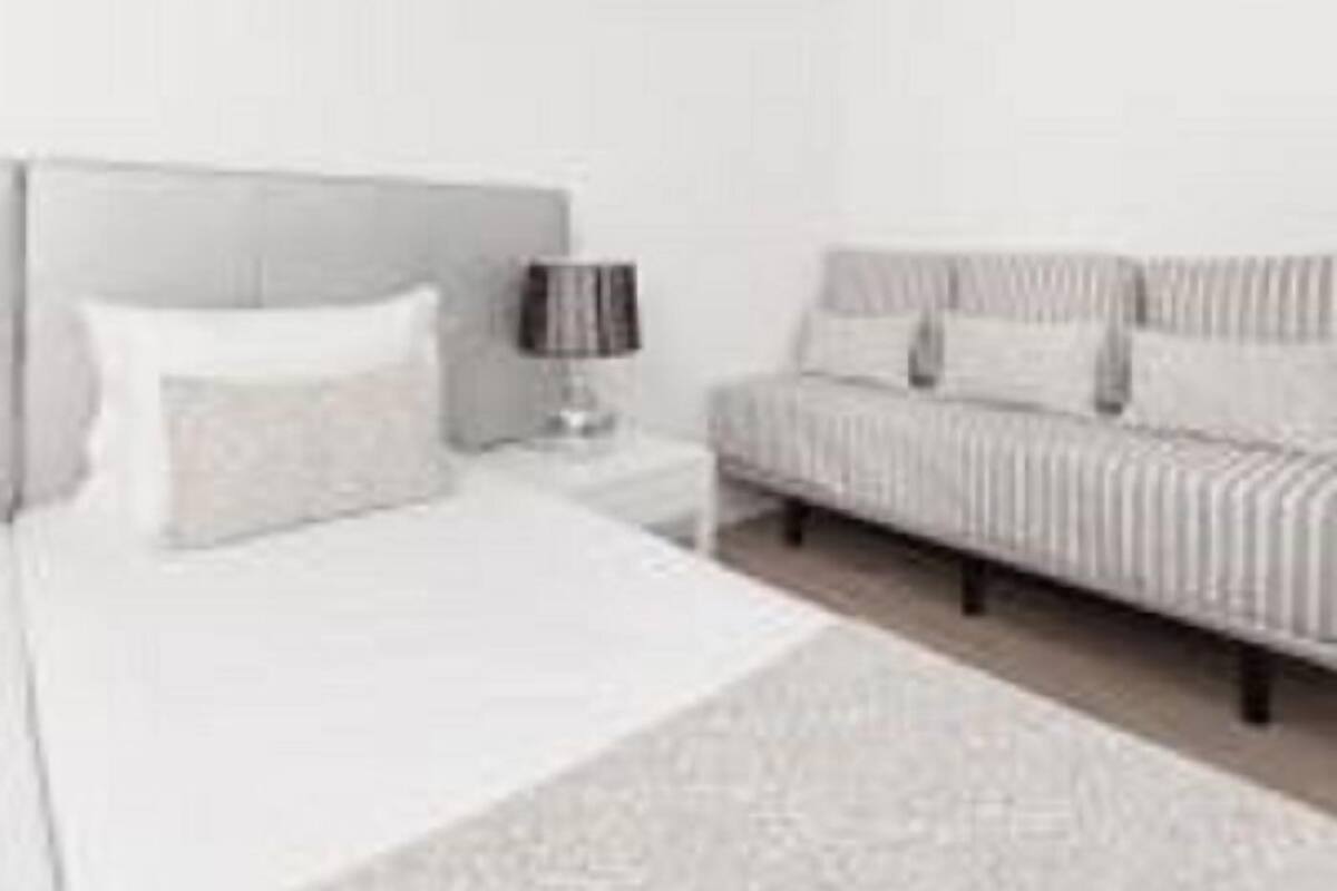 Ein modernes Schlafzimmer mit Bett, Nachttisch und einer Couch.