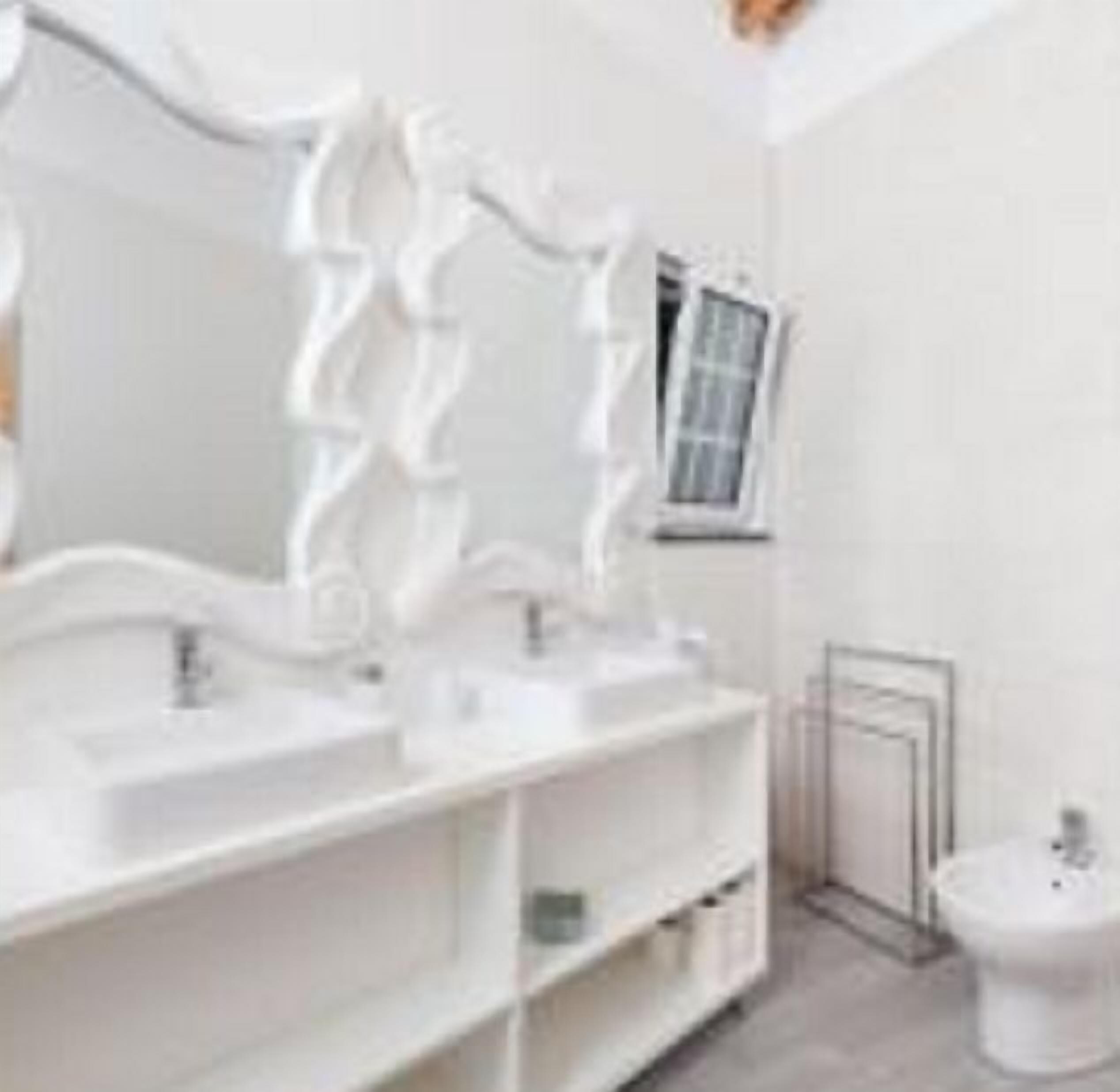 Un baño con tocador blanco, un espejo grande y un inodoro.