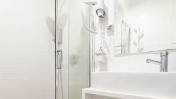 A modern bathroom with a glass shower enclosure, a white sink, and a mirror above the sink.