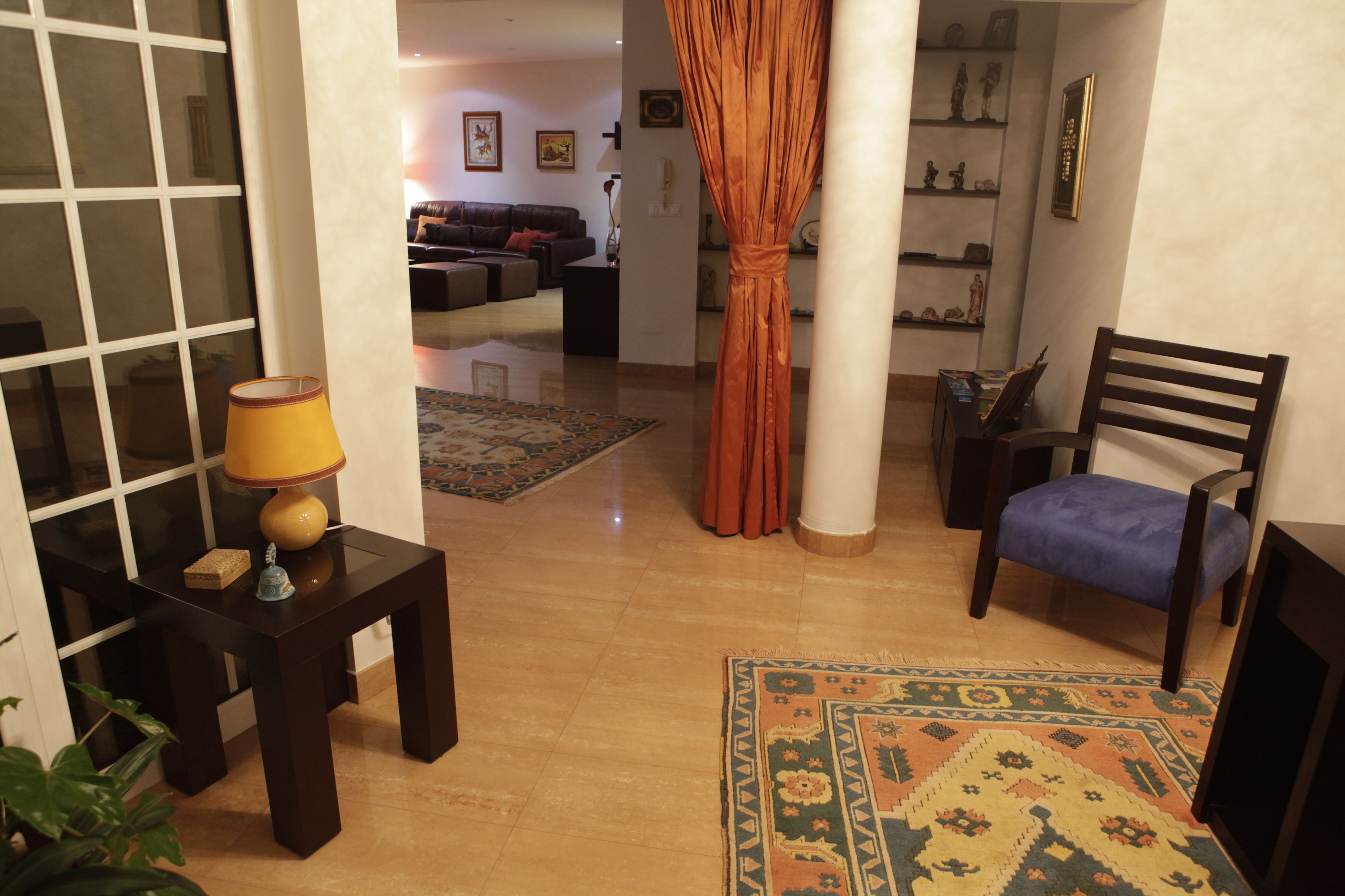 A living room with a sofa, a chair, a lamp, a rug, and a curtain.