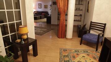 A living room with a sofa, a chair, a lamp, a rug, and a curtain.