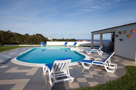 Una piscina al aire libre, sillones reclinables de piscina