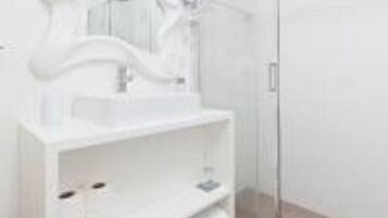 Um banheiro moderno com toucador branco, box de vidro e espelho curvo e elegante.