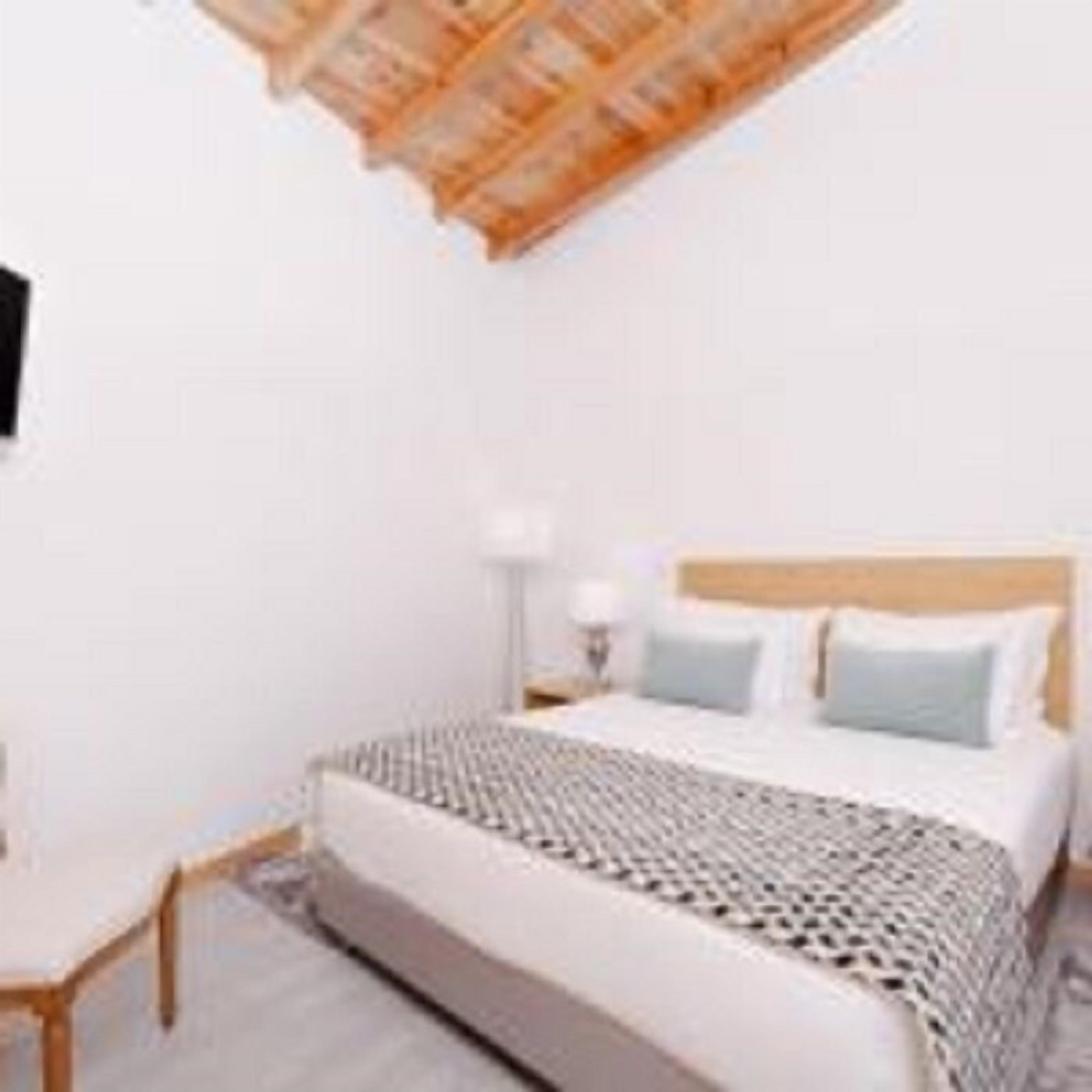 Camera da letto con un letto, un comodino, una lampada e un soffitto a falde.