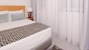 A hotel room with a bed, a nightstand, and a window with curtains. - Pico Dreams - Sportfish (Sao Roque do Pico)