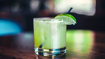 A glass of a green beverage with a lime wedge on a wooden surface.