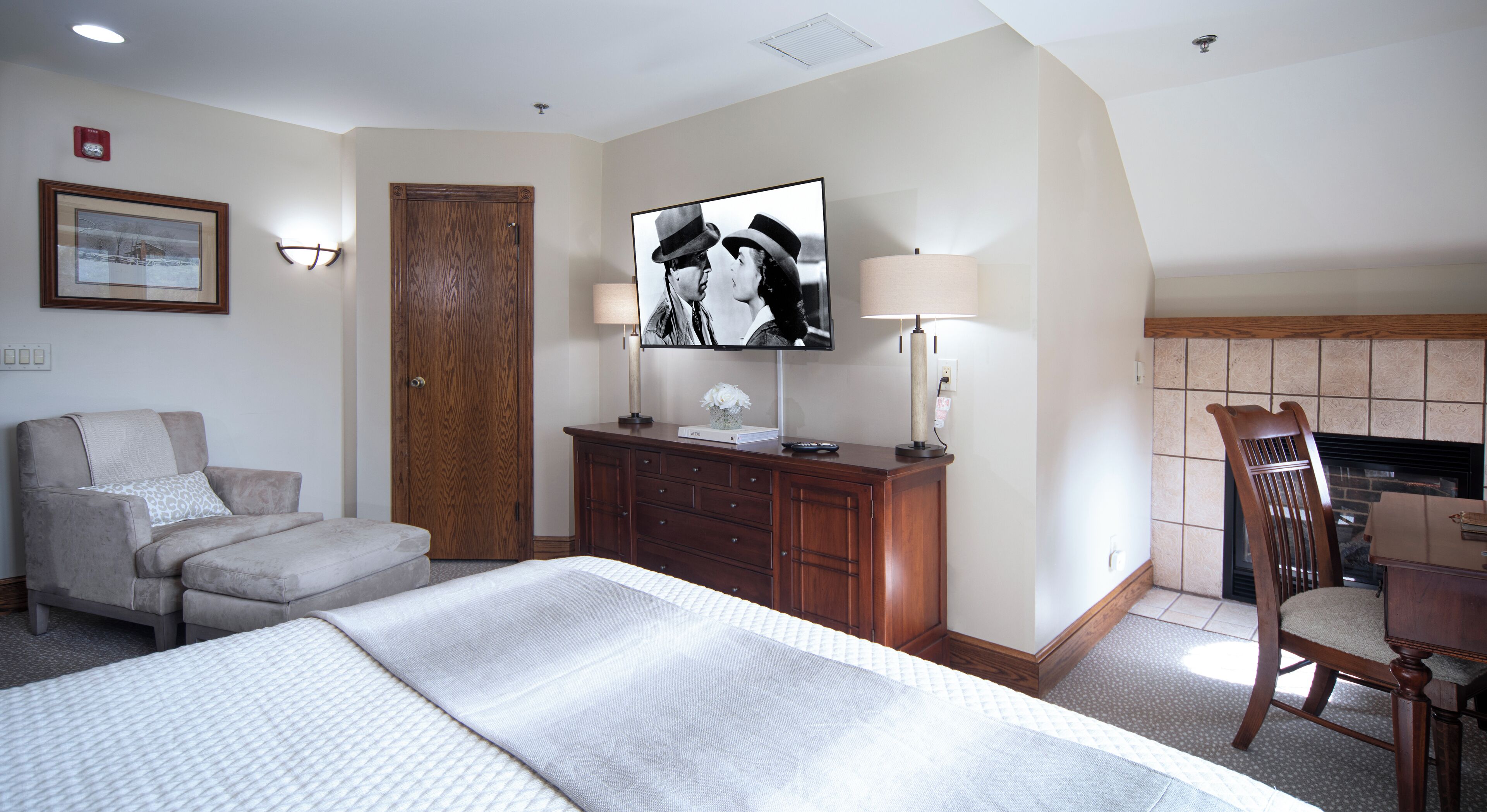 Una habitación de hotel con una cama, un escritorio, una silla, un televisor y una chimenea.