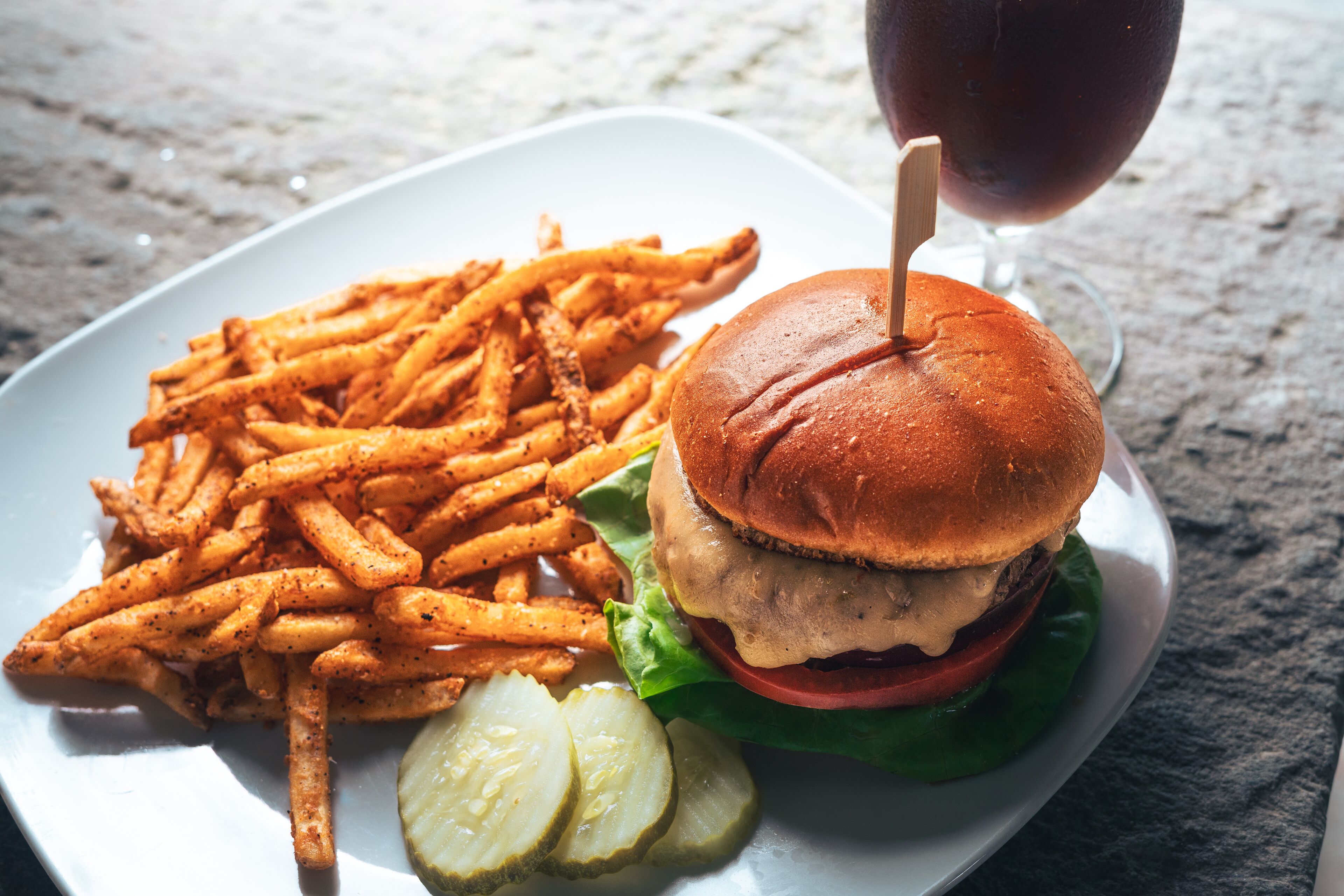 Un plato con una hamburguesa, papas fritas y pepinillos.