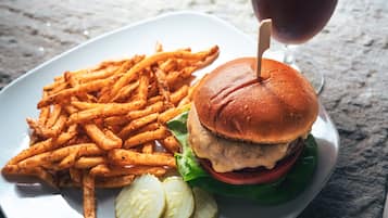 Un plato con una hamburguesa, papas fritas y pepinillos.