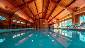 An indoor swimming pool with wooden beams, chairs, and potted plants. - Chetola Resort (Blowing Rock)