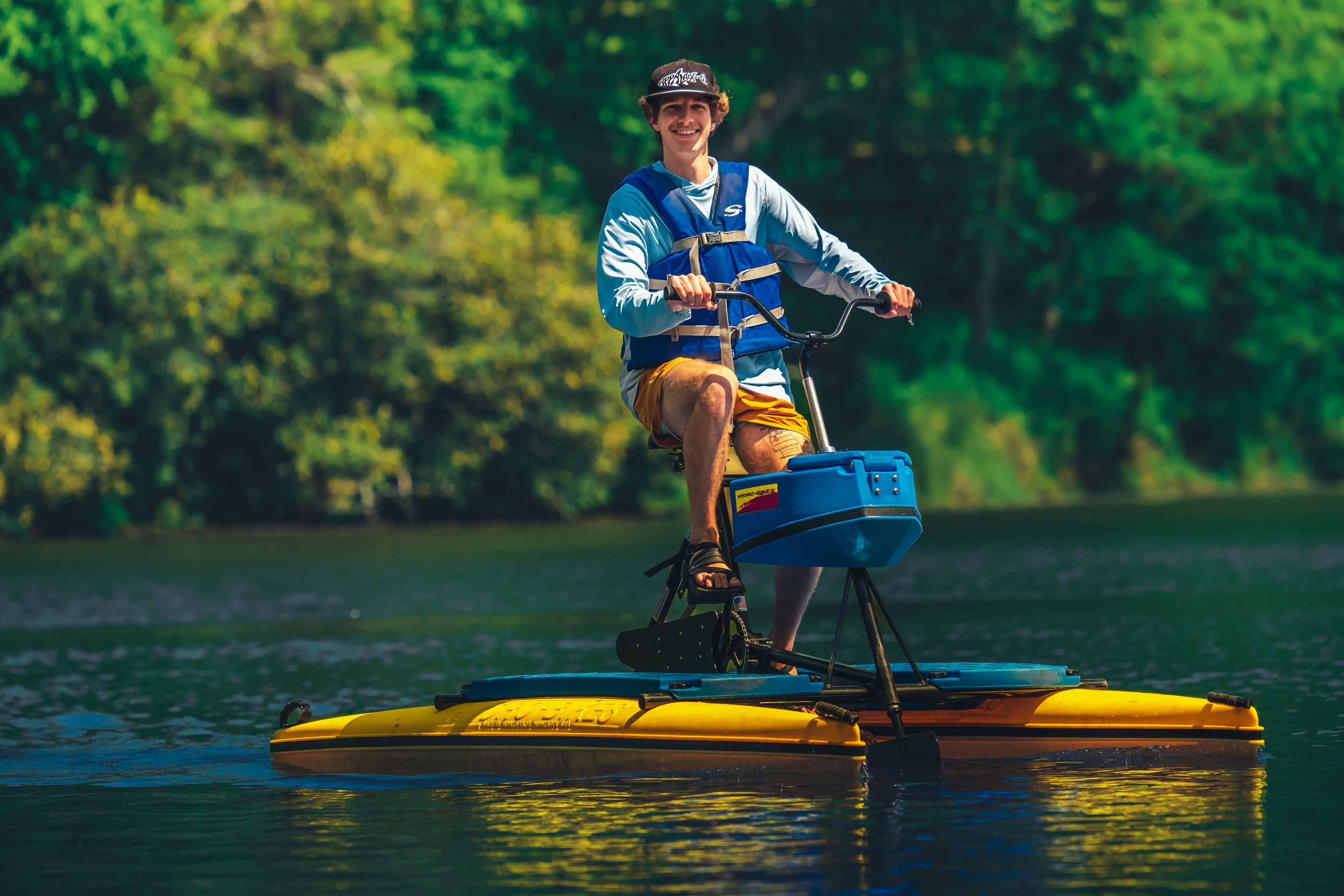 A person on a yellow inflatable raft in a body of water with trees in the background.