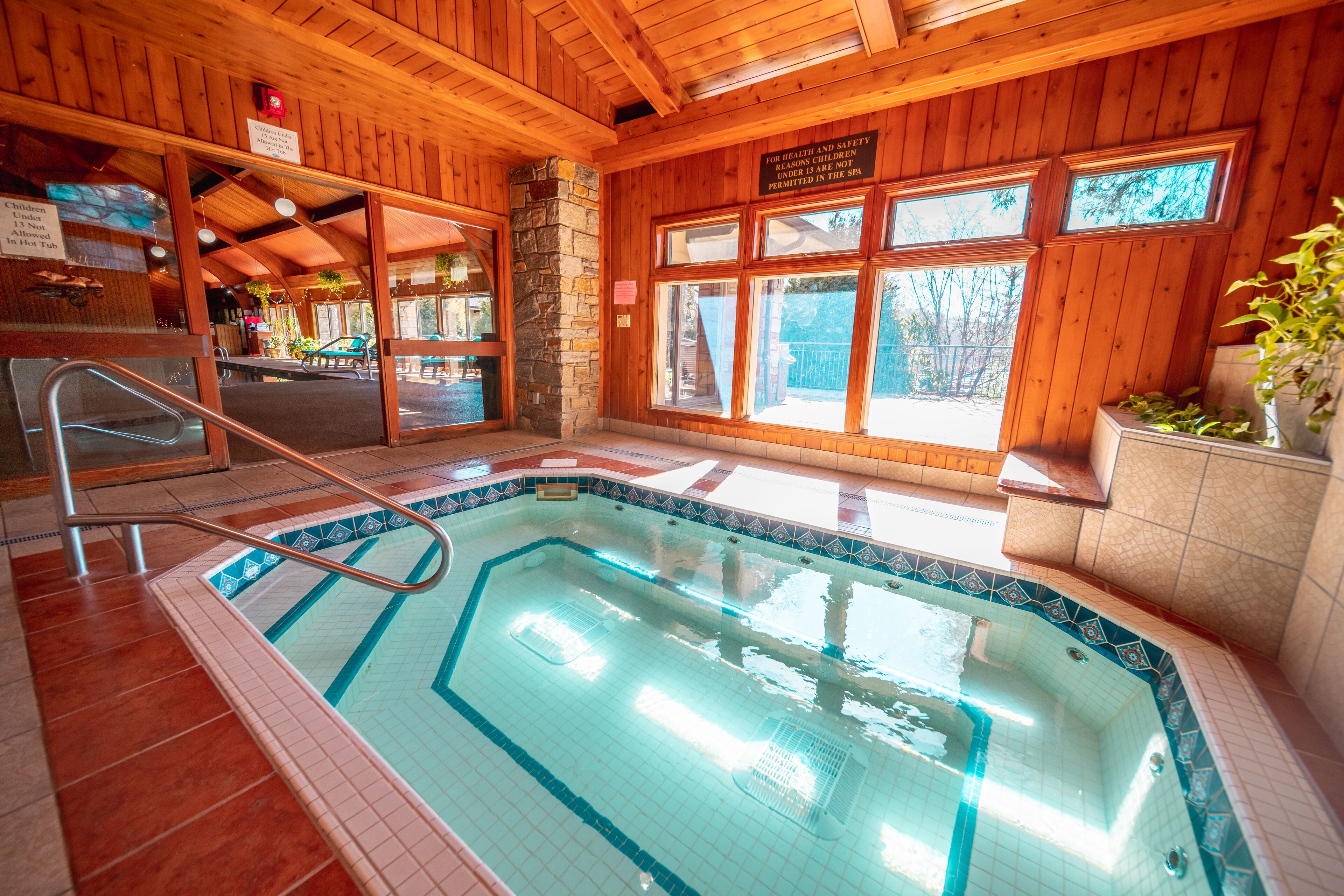 Une piscine intérieure avec des murs en bois et un pilier en pierre.
