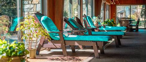 A sunlit outdoor seating area with wooden lounge chairs and potted plants.