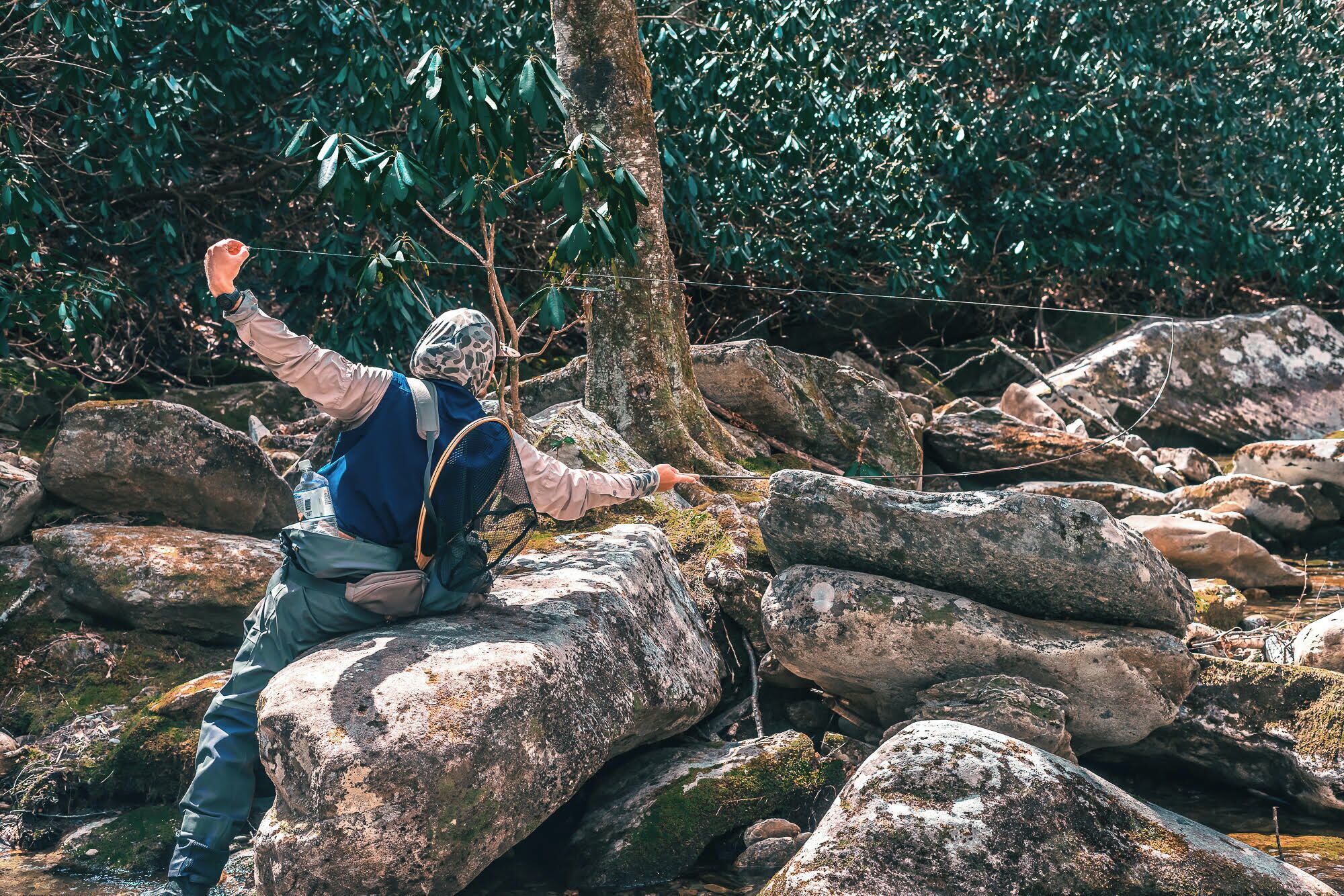 A person in outdoor gear, navigating a rocky terrain with a backpack.