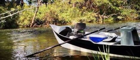 A small boat with a motor and a container on the shore.