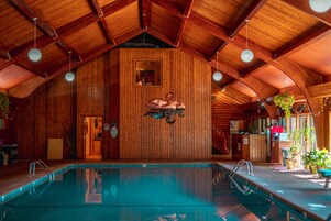 A wooden interior with a pool, wooden beams, and hanging plants.