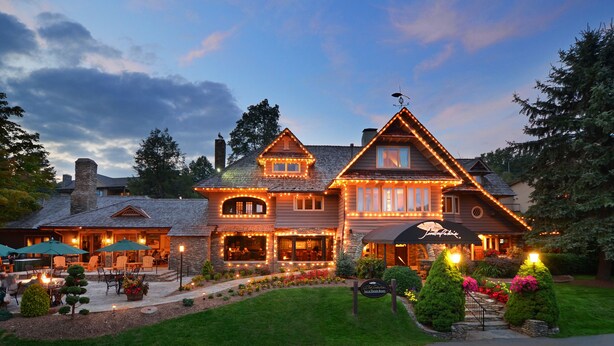 A large, two-story house with a well-lit exterior, a stone chimney, and a landscaped front yard with a pathway leading to the entrance. - Chetola Resort (Blowing Rock)