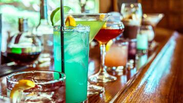 Un bar con diversas bebidas, incluyendo un vaso alto con una rodaja de lima y un trago verde.