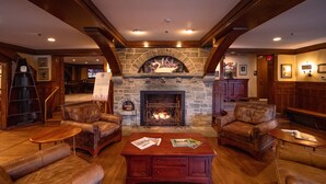 A cozy lobby with leather sofas, a wooden coffee table, and a stone fireplace. - Chetola Resort (Blowing Rock)