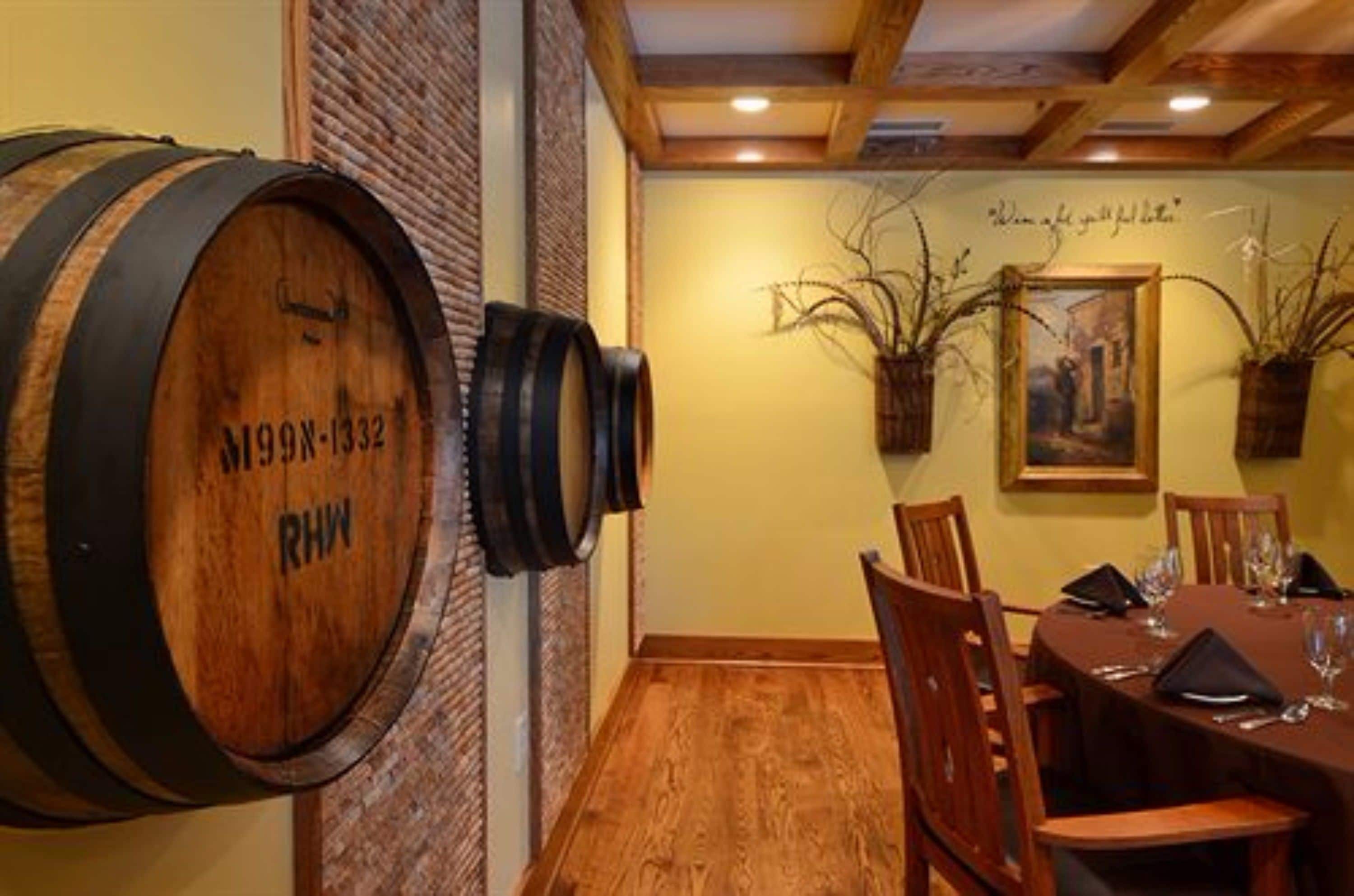 A dining area with wooden barrels, a brick wall, and a table set for dining.