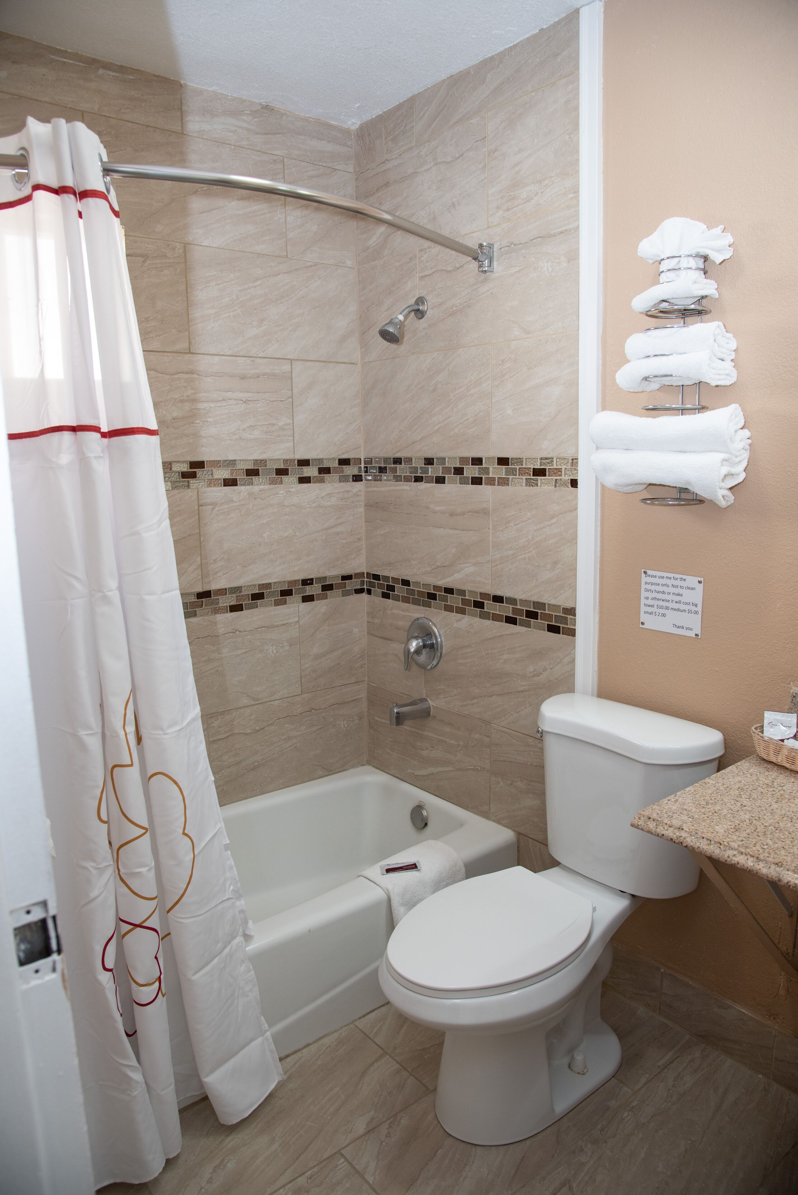 A bathroom with a shower, bathtub, toilet, and a towel rack with towels.