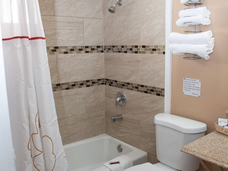 A bathroom with a shower, bathtub, toilet, and a towel rack with towels.