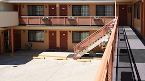 A two-story motel with a central staircase, balconies with flower boxes, and a parking area.