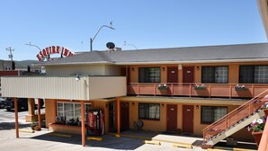 A motel with a 'Vacancy' sign, a Coca-Cola vending machine, and a staircase with flower boxes.