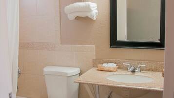 A bathroom with a toilet, sink, and mirror.