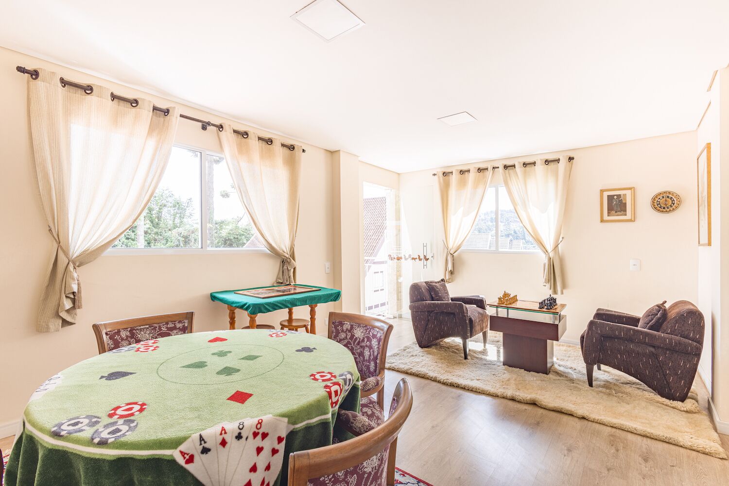Un coin repas avec une table dressée pour quatre personnes, une nappe verte ornée de cartes à jouer et deux chaises.